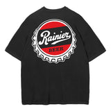 A black short-sleeve t-shirt with a large circular graphic on the back. The graphic features a red and black background with a white bottle-cap border and the text 'Rainier BEER' in white.